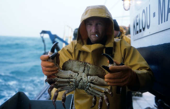 un pêcheur sur son bateau montre un dormeur qu'il vient de sortir de la mer