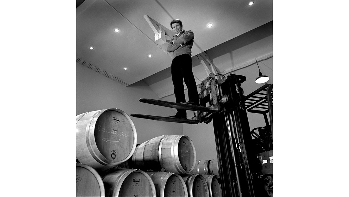 Portrait en noir et blanc de Jean-Christophe Mau, Vigneron du Château Brown (Pessac Léognan - Cru classique d'Yvon Mau) debout sur un chariot élévateur et photographié en contreplongée ; © Richard Nourry